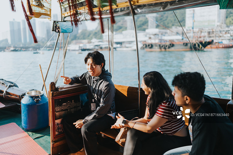 一名年轻的中国男导游向印度游客解释舢板船的细节图片素材