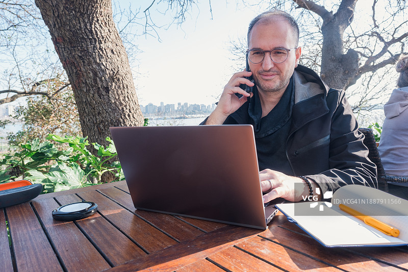 男子在户外咖啡馆上网，拥抱混合工作模式图片素材