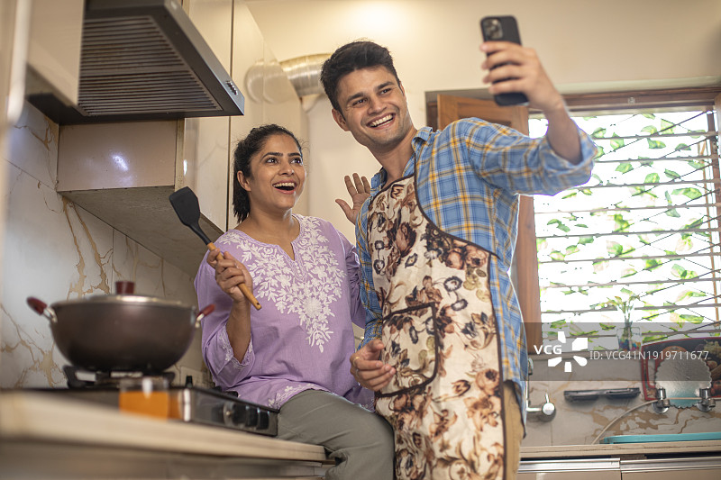 幸福的夫妇在厨房用手机查看菜谱图片素材