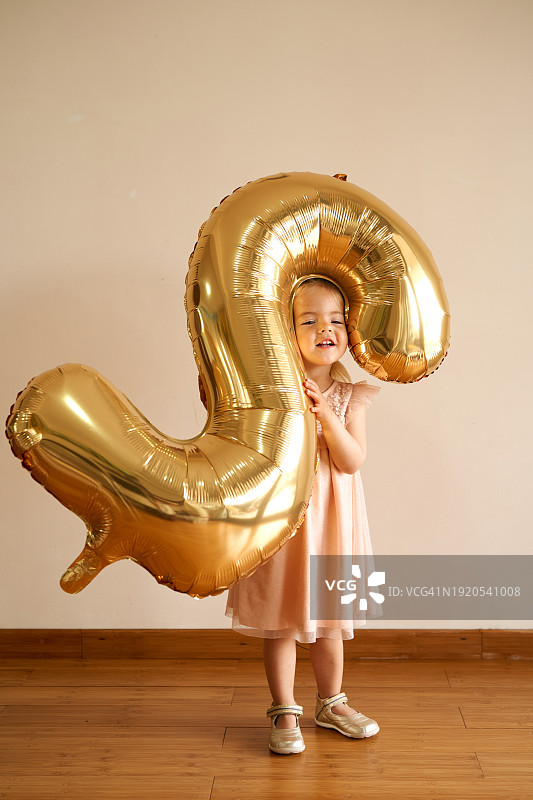小女孩站在一个房间里，怀里抱着一个充气二号图片素材