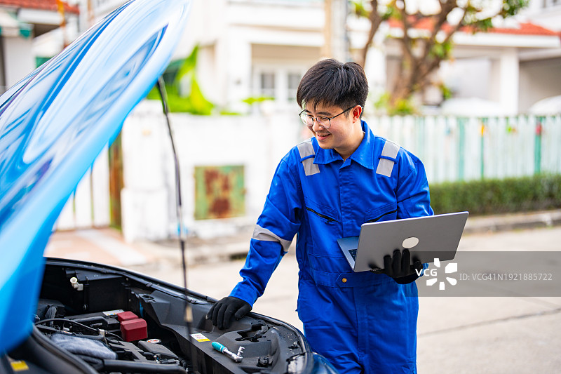 一个热爱汽车的亚洲男人在业余时间热衷于修理汽车。他是个业余汽车技师。图片素材