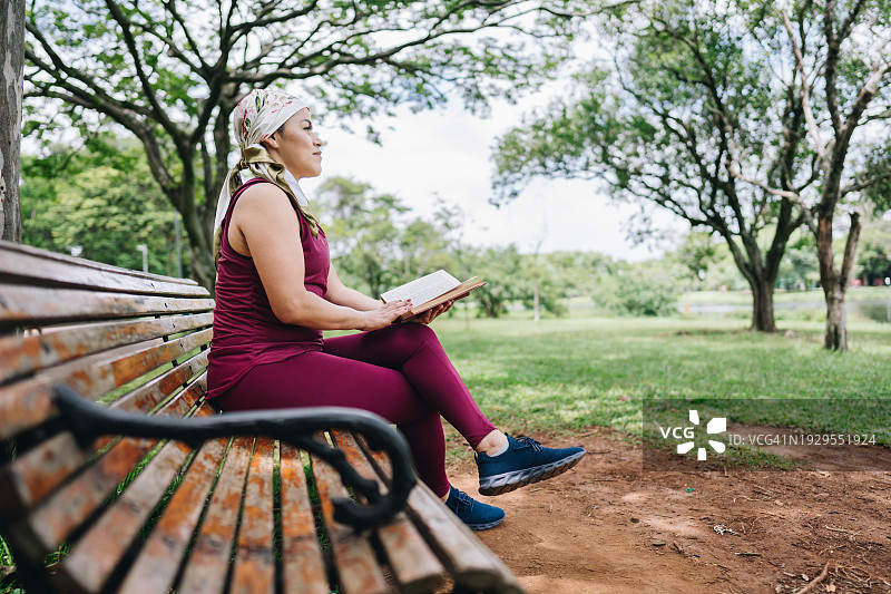 一个与癌症抗争的成熟女人，在公园里沉思着，读着书图片素材