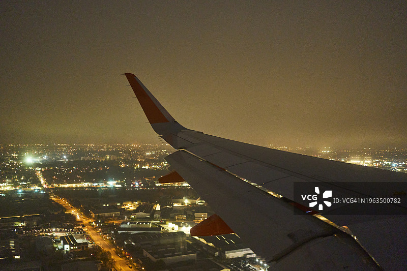 从高角度和正面的窗户俯瞰城市上空的飞机机翼图片素材