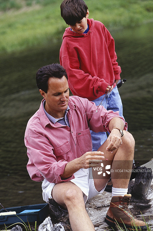 父亲和儿子(10-11)在湖边搭钓竿图片素材