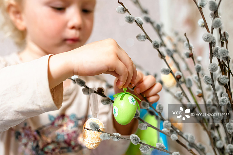 小女孩用柳枝装饰复活节彩蛋，特写图片素材