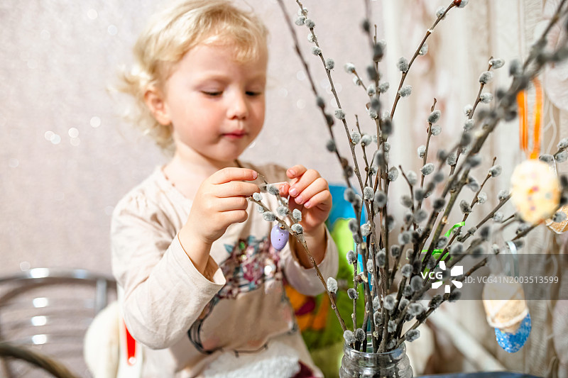 小女孩在家里用柳枝装饰复活节彩蛋。图片素材
