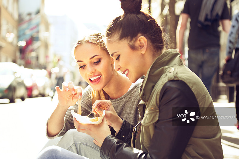 女性朋友在街上吃薯片图片素材