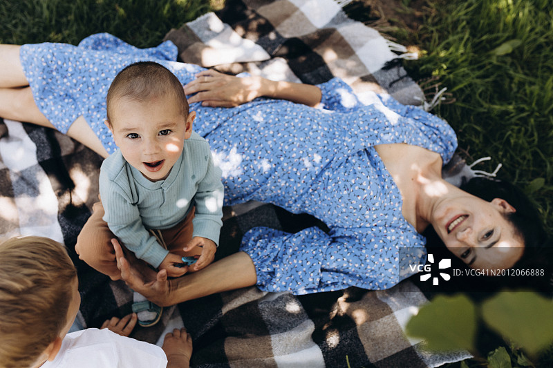 幸福的母亲带着两个儿子躺在毯子上图片素材
