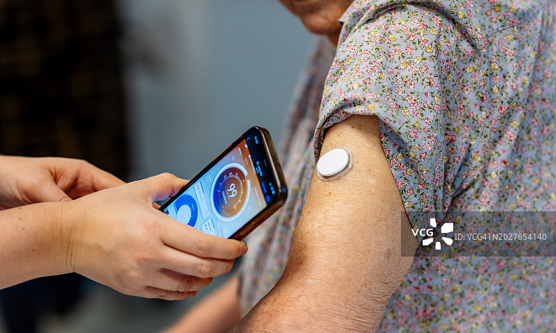糖尿病专家教老年患者如何将智能手机连接到连续血糖监测仪。图片素材
