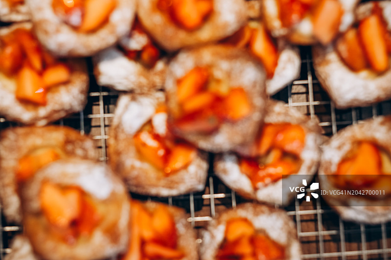 模糊的背景展示了糖粉桃子泡芙糕点，在温暖的烘焙氛围中。图片素材