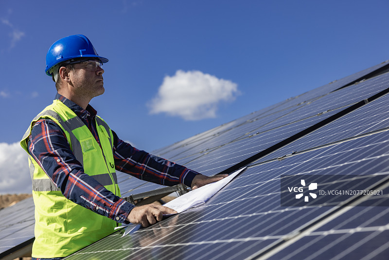 太阳能农场工程师回顾蓝图:绿色能源发电的太阳能电池板的规划和安装图片素材