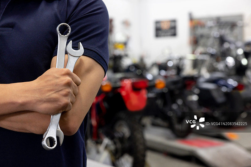 在汽车修理店，一个机械师拿着扳手的特写镜头图片素材