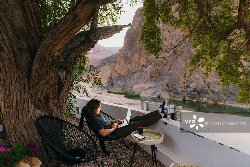 在山区旅行期间，女性自由职业者在户外用笔记本电脑工作图片素材