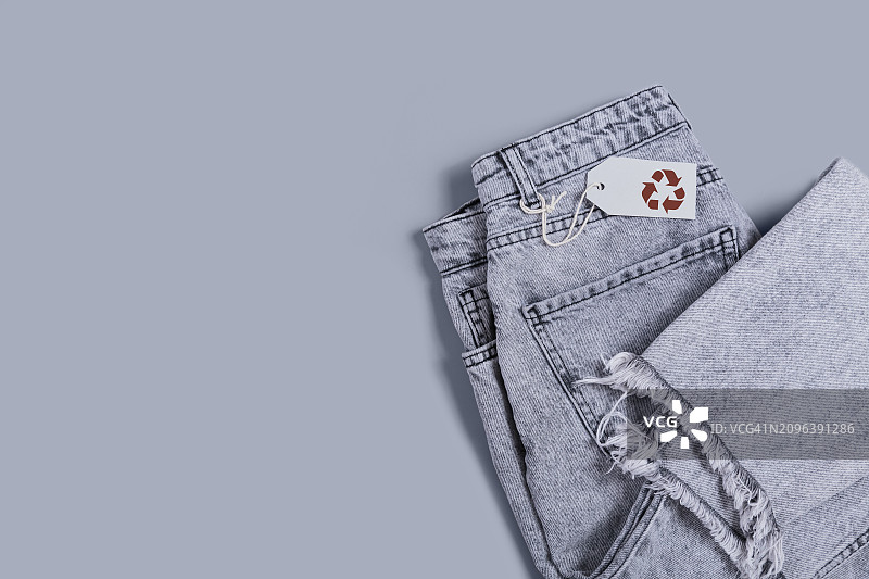 灰色牛仔裤和标签与回收标志在灰色背景图片素材