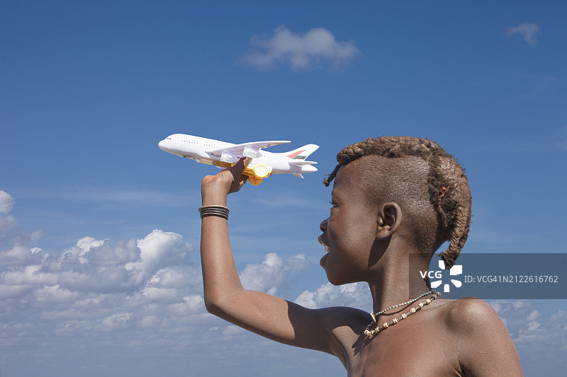 纳米比亚。小辛巴男孩在玩玩具飞机。图片素材