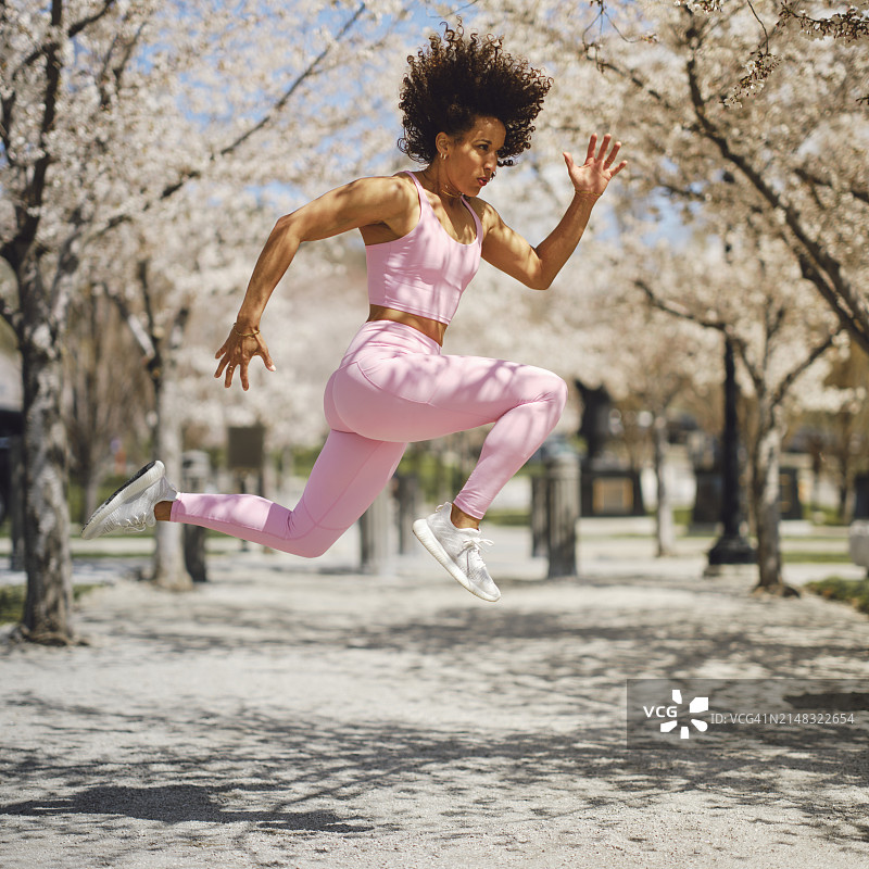 女子运动员在春天的花丛中跳跃图片素材