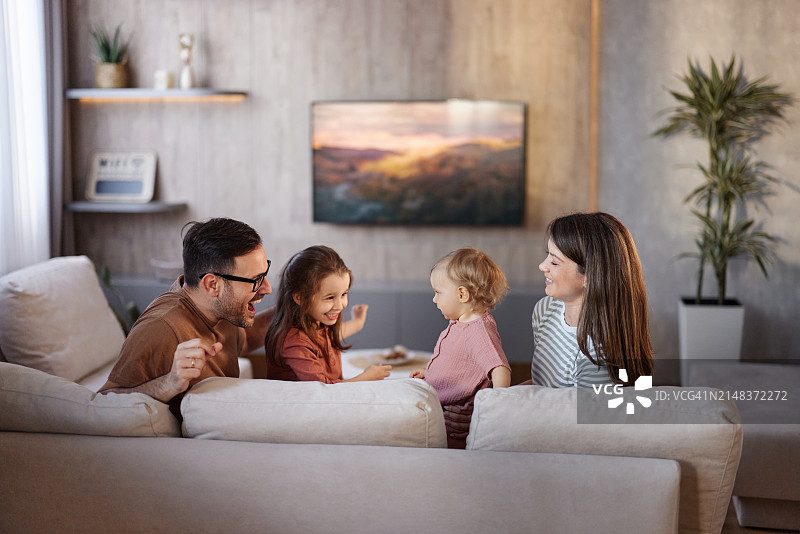 幸福的一家人在家里的沙发上玩耍。图片素材
