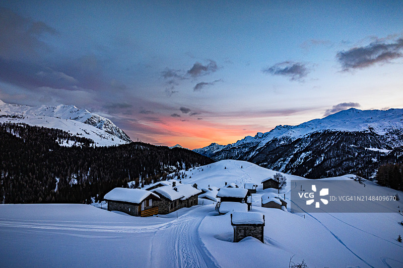 日落时被雪覆盖的山间小屋图片素材