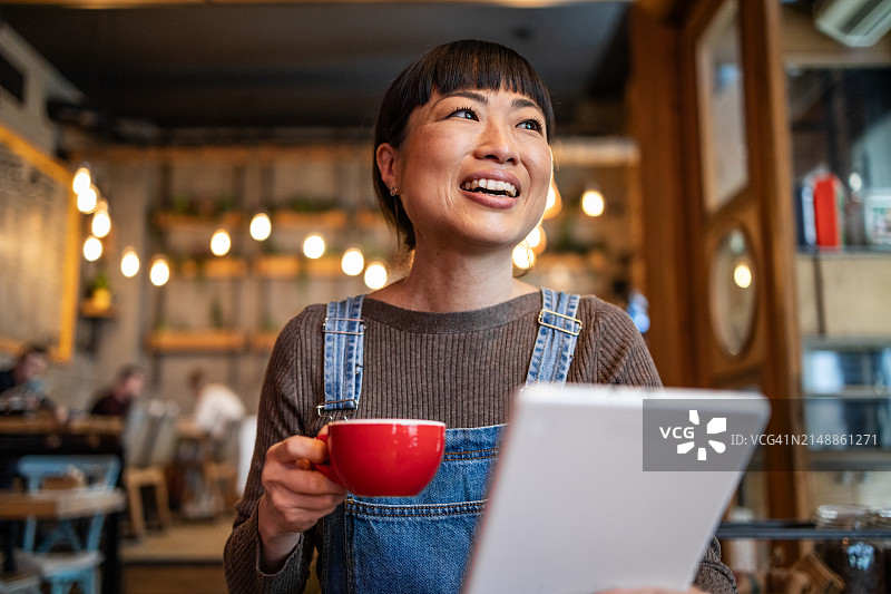 一名日本女子在咖啡馆喝咖啡，用平板电脑与朋友进行视频通话图片素材