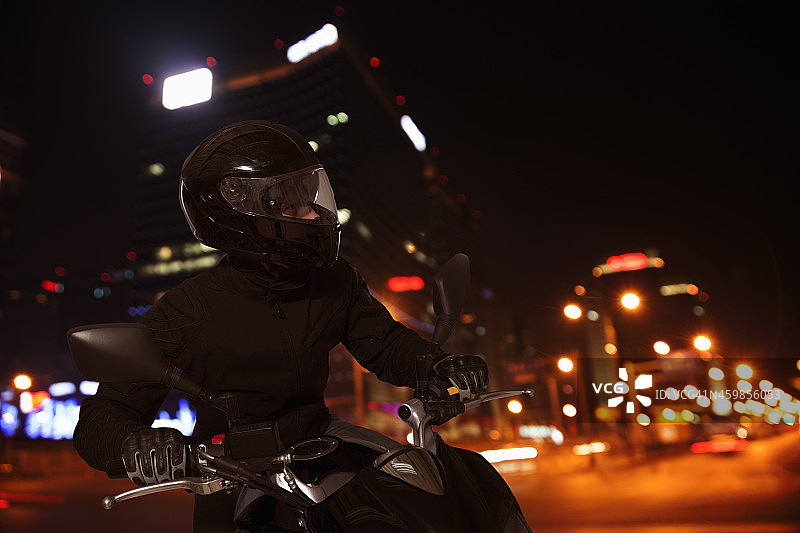 一个喜欢冒险的年轻人在夜里骑摩托车图片素材