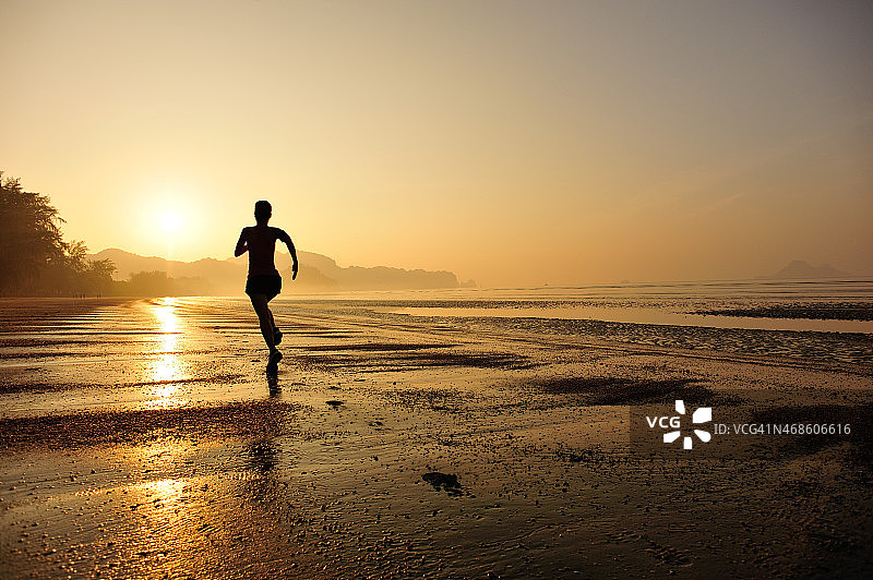 年轻的健身女性在海滩上跑步图片素材