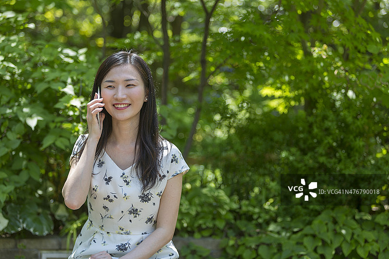 在日本花园中使用手机的女人图片素材