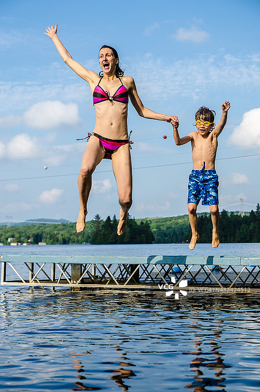 母亲和儿子从码头跳到湖里图片素材