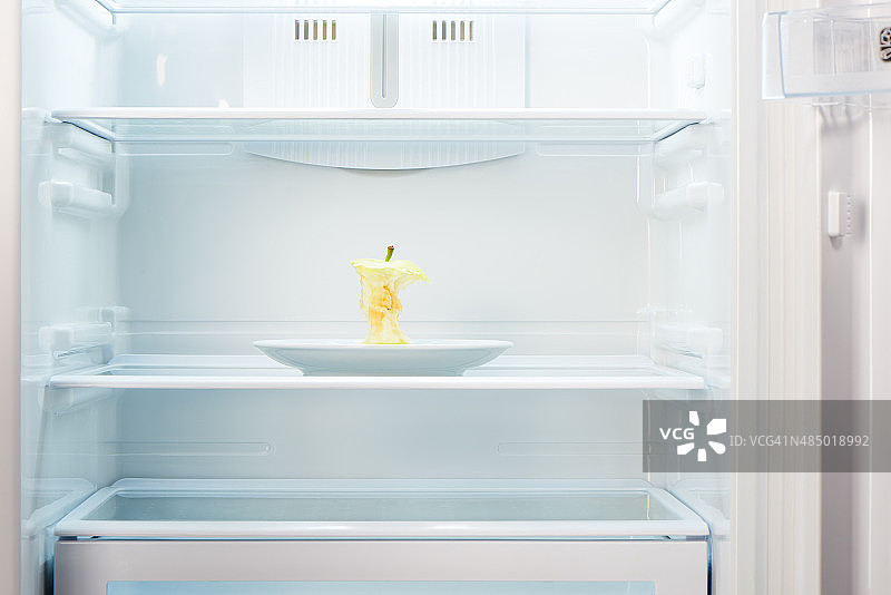 苹果核放在空冰箱的白色盘子上图片素材