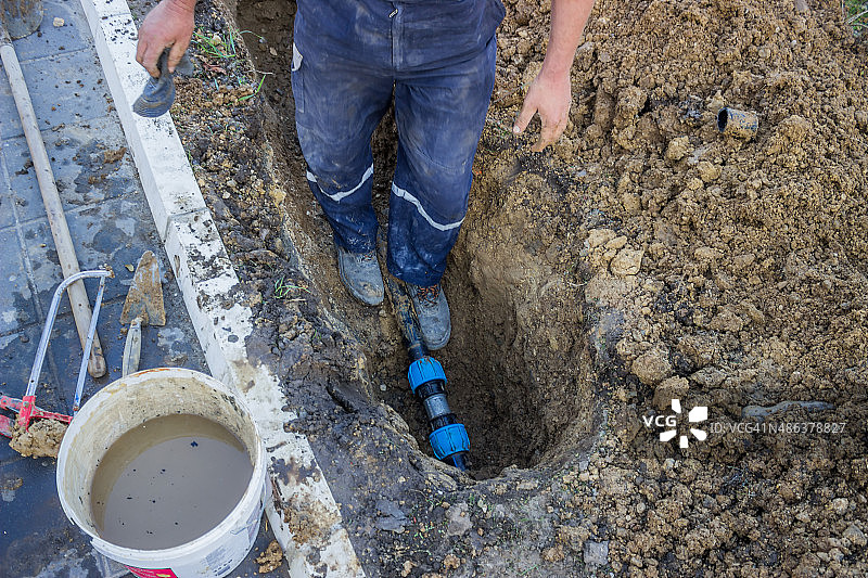 公用事业工人在沟里修理破裂的管道图片素材