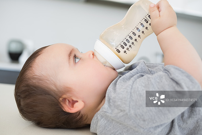 婴儿躺在柜台上喝牛奶图片素材