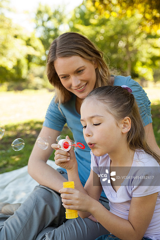 妈妈和她的女儿在公园吹肥皂泡图片素材
