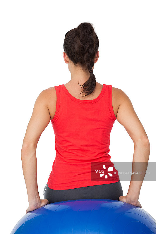 一个健康的女人坐在健身球的后视图图片素材