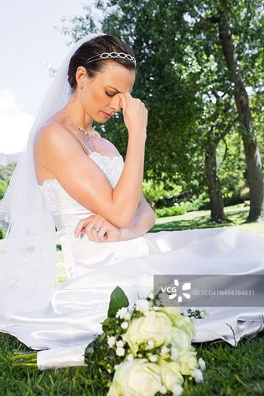 沮丧的新娘坐在花园里图片素材