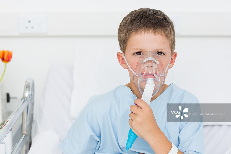 男孩戴着氧气面罩躺在病床上图片素材