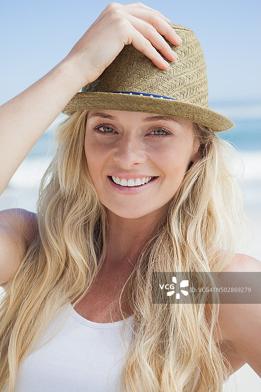 时髦的金发女郎在海滩上对着镜头微笑图片素材