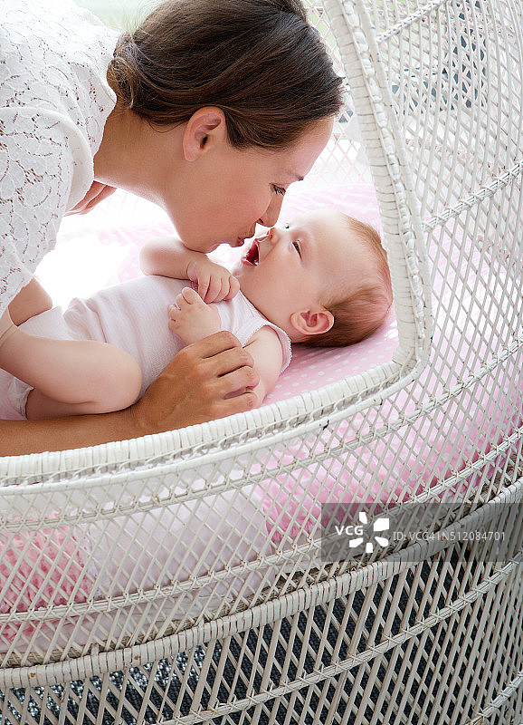 慈爱的母亲在床上亲吻婴儿图片素材