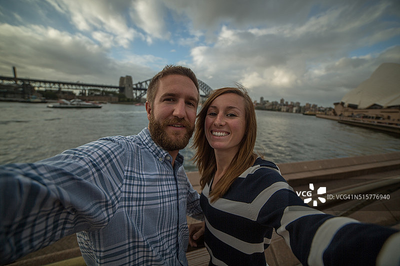 一对年轻夫妇在悉尼港拍自拍照图片素材