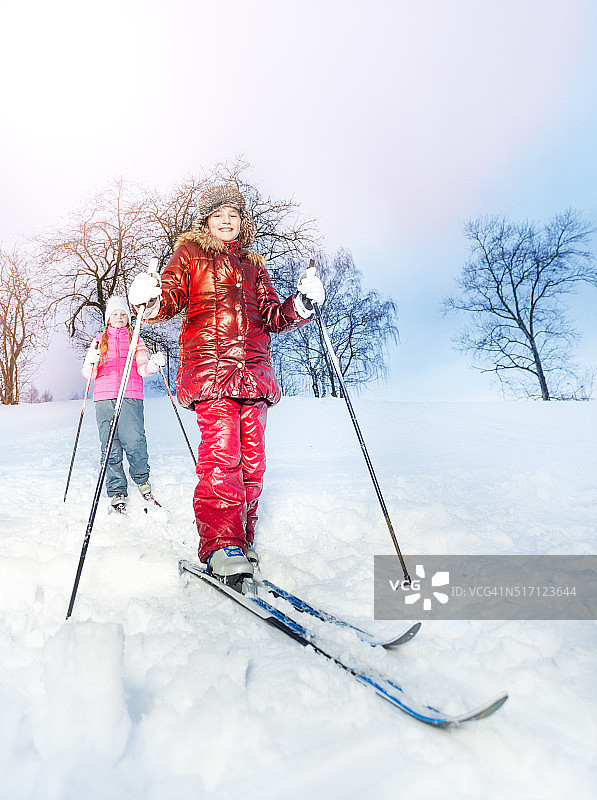 冬天的一天，两个女孩在空中滑下山坡图片素材