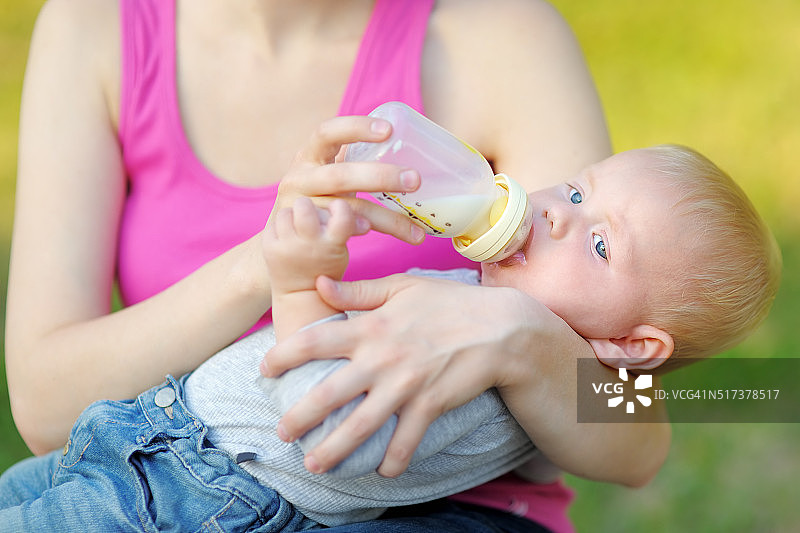 婴儿从妈妈手里的奶瓶里喝牛奶图片素材