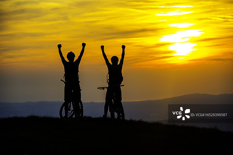 骑自行车的人在日落时举手图片素材