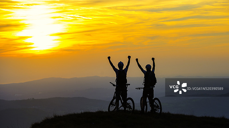 骑自行车的人在日落时举手图片素材