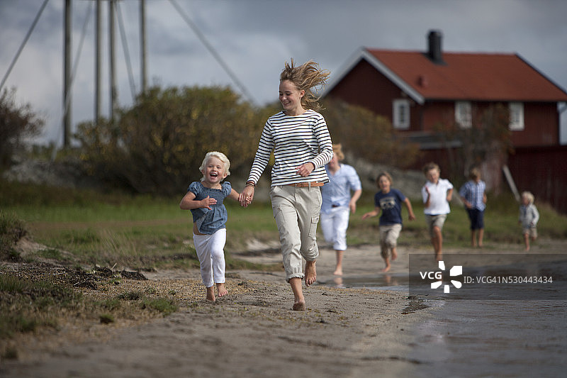 一家人在瑞典瓦斯库斯滕的海滩上奔跑图片素材