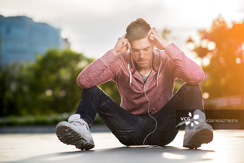 头疼的失意男人用耳机听音乐。图片素材