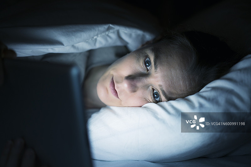 晚上在床上用平板电脑的女人图片素材