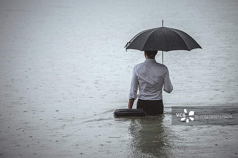 英俊的男人站在水里，在雨中撑着伞图片素材