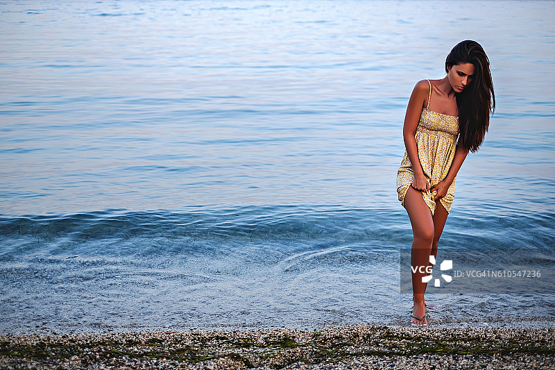 女孩从水里走出来，撩起裙子图片素材