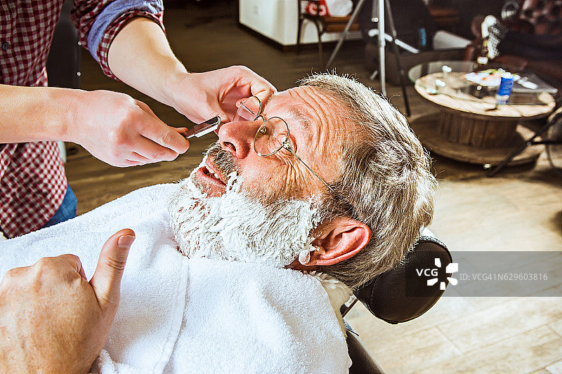 老人在理发店里拜访发型师。图片素材