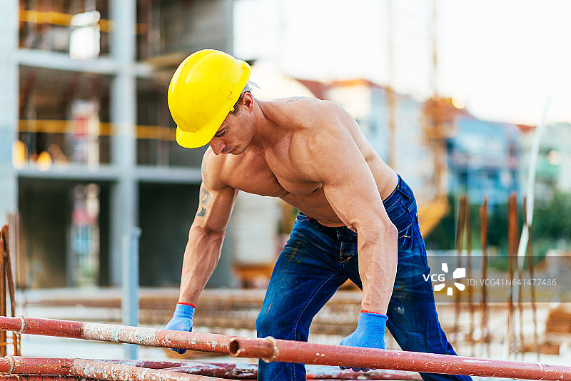 强壮、肌肉发达的手工建筑工人在施工平台上工作图片素材