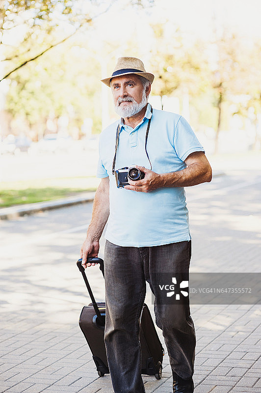 带着行李和相机旅行的老人。旅游的概念图片素材
