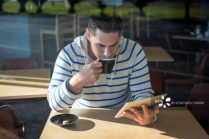 一边喝咖啡一边用平板电脑的男人图片素材